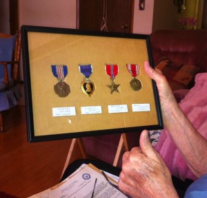 Nyle Smith holding a display of his medals, including the Soldiers Medal (left).