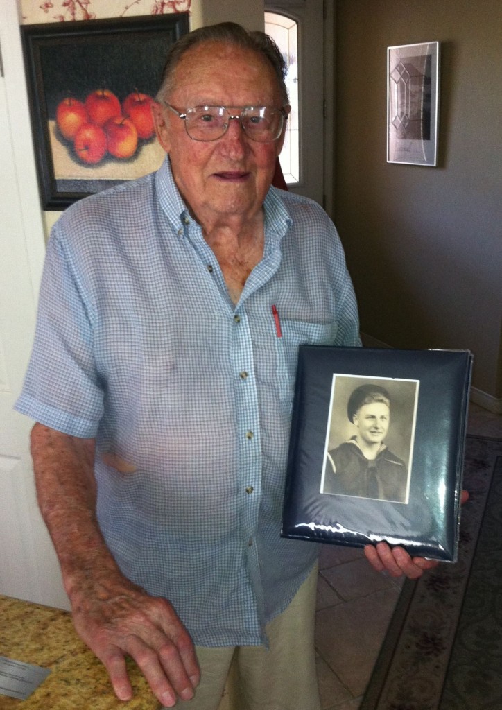 94-year-old Willis Shepard holding a photo of himself as a young sailor during WWII.