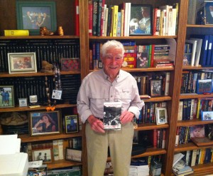 94-year-old Jerry Countess holds the book he wrote, in front of a small fraction of the books he's read.